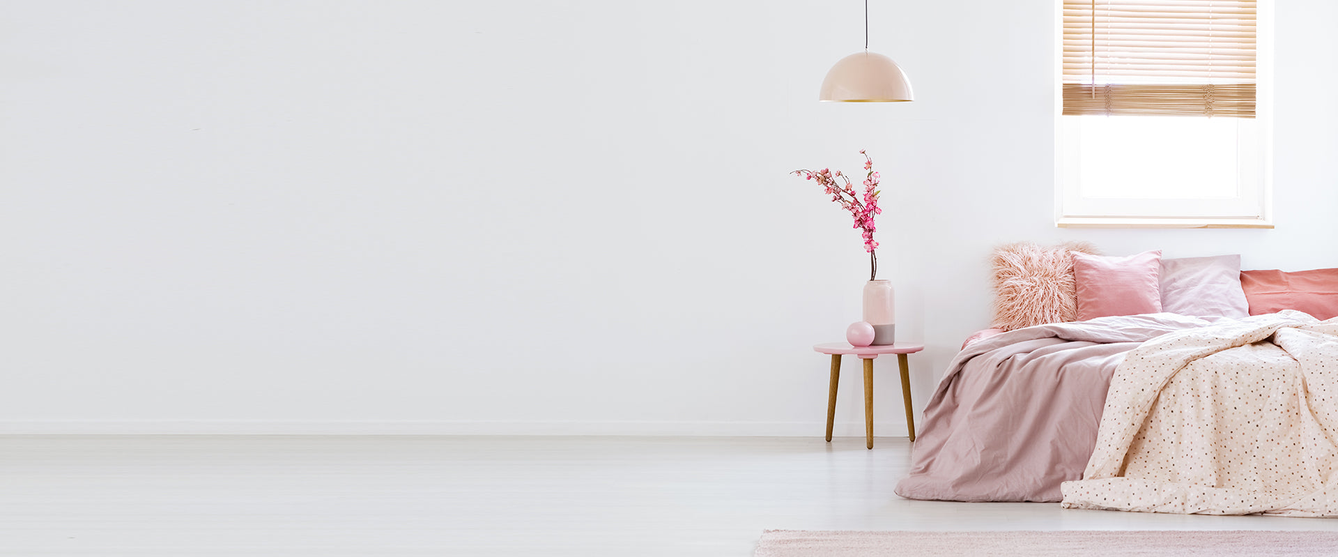 a pink blanket and a vase with flowers in a white room